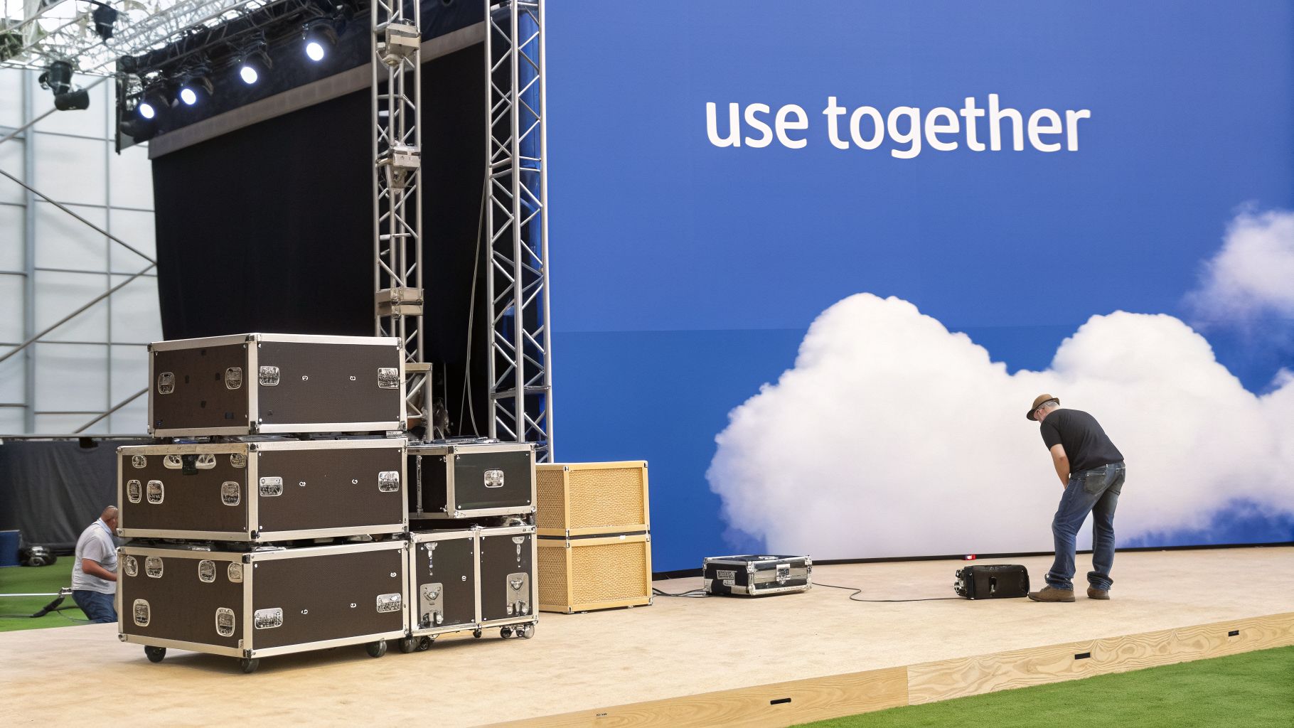 Technicians set up sound equipment cases and a stage with a blue screen displaying 'use together' and clouds.